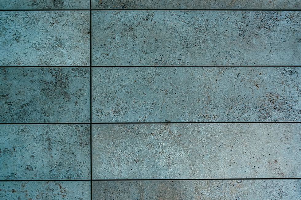 Blauwgrijze wandtegels met steenlook als inspiratie voor de wandafwerking van een badkamer.