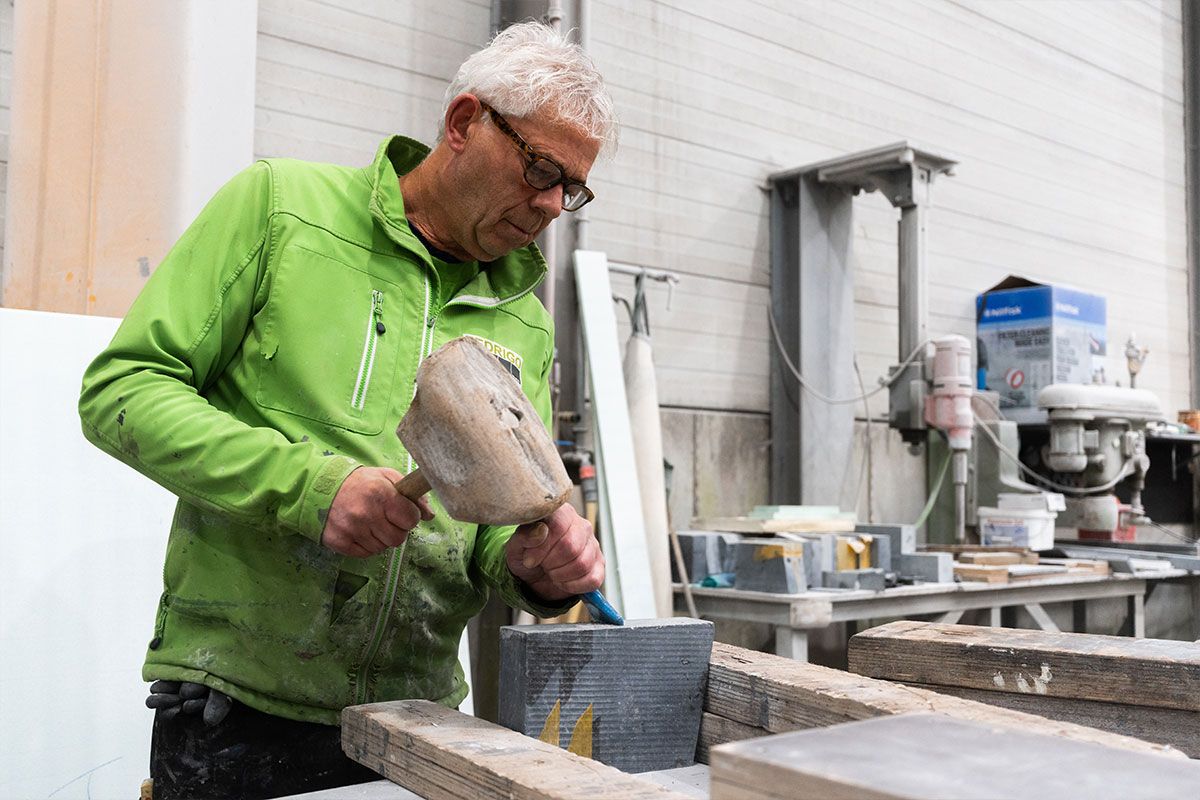 Vakman van Fedrigo bewerkt natuursteen met precisie in het atelier