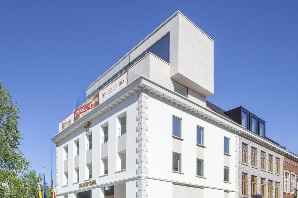 Hoekgebouw van Project Uilenspiegel in Hasselt met natuurstenen gevel in Sinaï Pearl